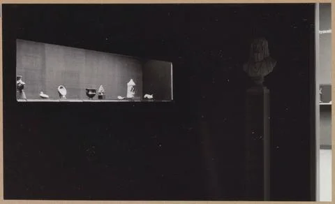 Angle of a room with a bust and a display case with eight objects under wh... Stock Photos