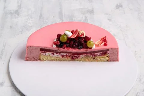 Angle shot of the half of a berry mouse pink cake decorated with berries on a tr 스톡 사진