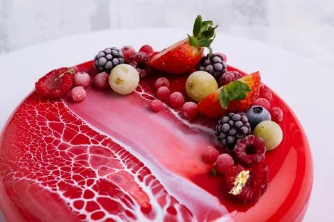 An angle shot of a mirror glaze cake decorated with berries. Stock Photos