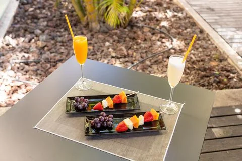 Angle shot of some fresh-cut fruits on wooden sticks and some cocktails on a 스톡 사진