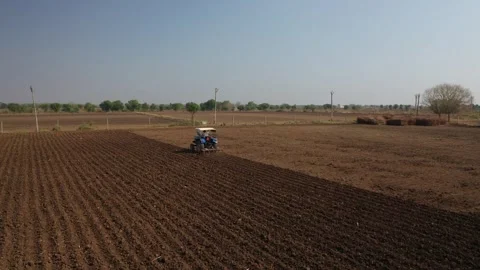 Angle tracking shot of a single blue tractor plowing a wide rural field Stock Footage 337198992