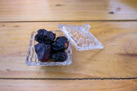 Angle view of dates on glassware over wooden surface. Stock Photos