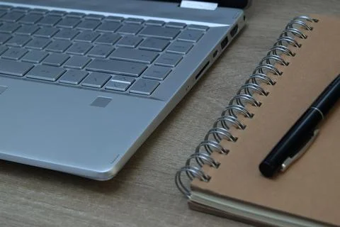 Angle view of laptop keyboard, notebook and pen on desk Stock Photos