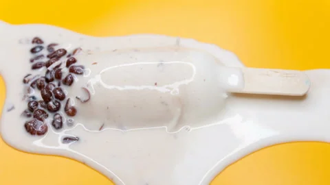 Angle view milkshake flavor popsicle with red beans melting on a yellow backg Stock Footage 163901011