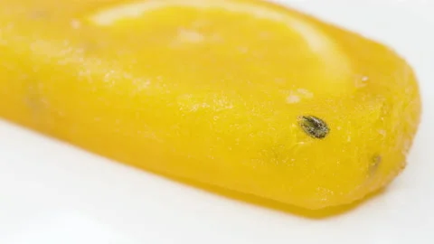 Angle view orange and passion fruit flavor popsicle with slice of orange melt Stock Footage 195287660
