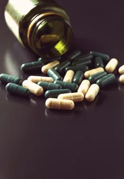 Angle view of pill bottle with green and white prescription medicine spilling Stock Photos