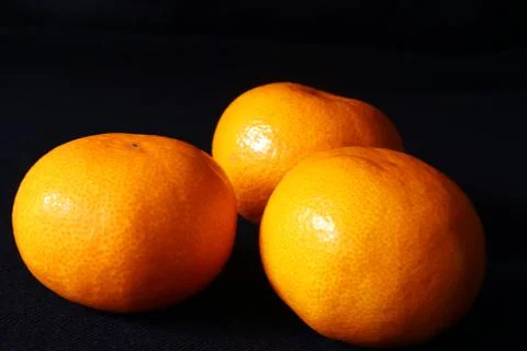 Angle view of Three orange mandarin fruits against black background,Scientifi Stock Photos