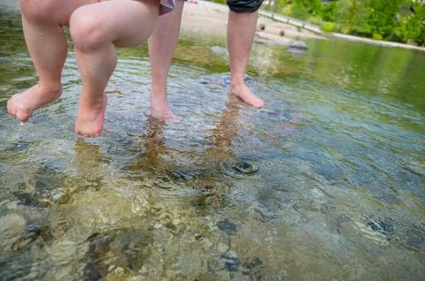 Angle view of unrecognizable child being lifted by parent across water. Stock Photos