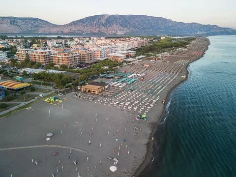 Angled Aerial View of Velipoja Beach, Umbrella Lines and Mountains Stock Photos