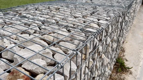 Angled close-up of a gabion wall filled with pale limestone rocks, showing Stock Footage 338003187