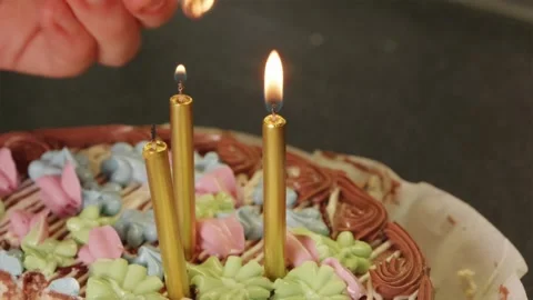 Angled close up of hand lighting birthday cake candles with matchstick Video stock 344877189