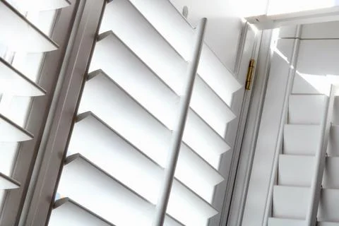 Angled full frame image of light shining through plantation shutters Stock Photos