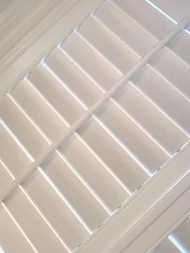 Angled full frame image of light shining through plantation shutters Stock Photos