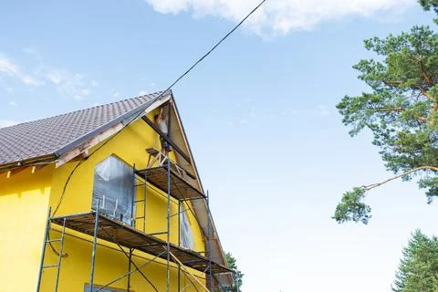 Angled house corner with timber installation, scaffolding stretches around .. Stock Photos