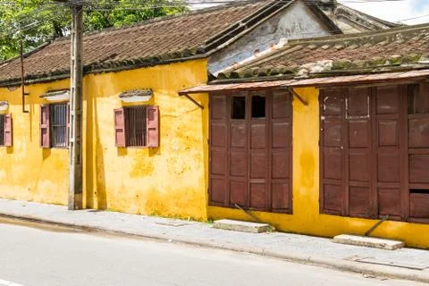 Angled view of bright yellow building with brown shutters in Hoi An, Vietnam Foto stock