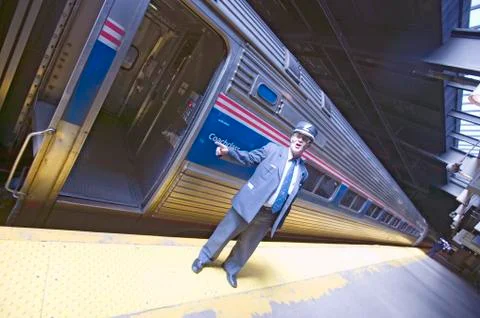 Angled view of conductor at Amtrak train platform announces All Aboard at East Stock Photos
