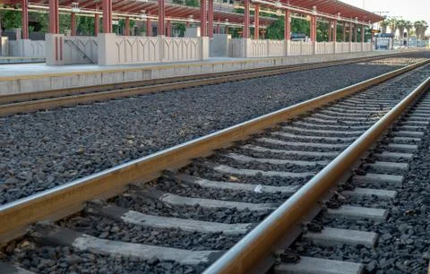 Angled view of empty locomotive train tracks at a station platform at sunset Stock Photos