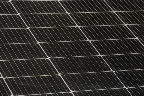 Angled view of a gray-background solar panel, arranged in a grid with dark .. Foto stock