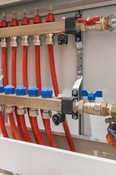Angled view of heating manifold with connected pipes inside cabinet. Fotos Stock