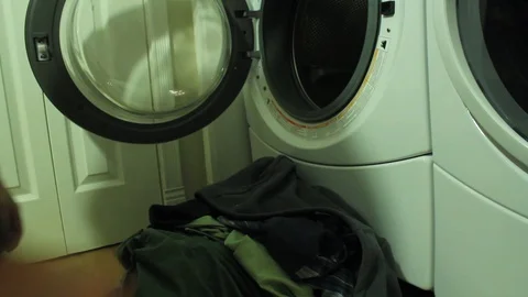 Angled view of loading laundry into a front-loader washing machine Stock Footage 92482623