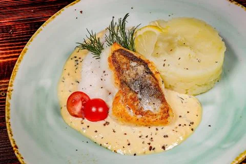 An angled view shot showcasing a fried fish fillet with mashed potatoes and c 스톡 사진