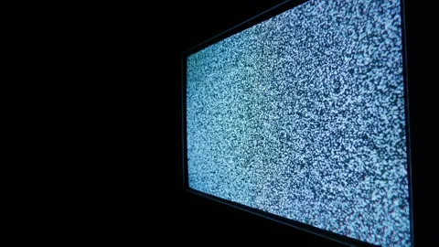 Angled View of a Television Screen Displaying Static Noise in a Dark Room Stockbeeldmateriaal 335634084