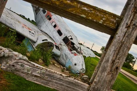 Angled view through fence of crashed airplane in field Stock Photos
