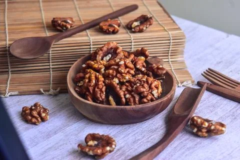 Angled view walnut kernel halves in wooden bowl for snacking or baking. Stock Photos