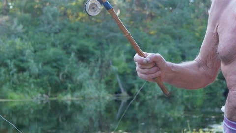 Angler Removes from the Hook a Small Fish Caught with an Old Bamboo Fishing Rod Stock Footage 167896829