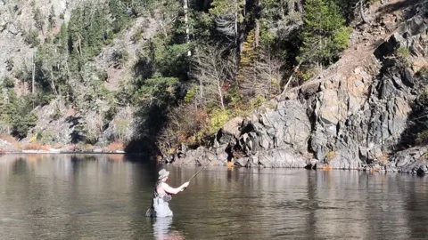 An angler rhythmically casts a fly rod in a pristine river Stock Footage 326979818