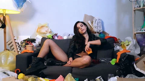 Angry and brutal looking young woman sitting on the couch and throwing garbage. Stock Footage 123532080