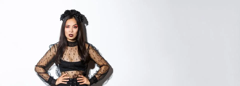 Angry and pissed-off asian female magician, evil witch in black dress and wreath Stock Photos