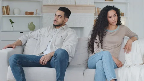 Angry arabic man sitting on sofa separately from sad caucasian wife, boyfriend Stock Footage 155350278