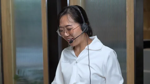 Angry asian receptionist using headset tell off customer and showing Middle.. Stock Footage 252953115