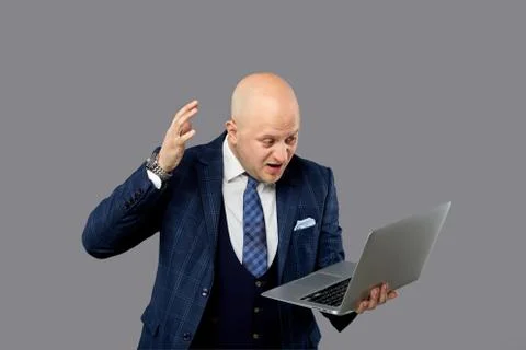 An angry bald man screams and raises his hand up. Looks at the screen. Foto stock