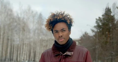 Angry black guy portrait close up african man looking at camera in winter 4K. Stock Footage 123881376