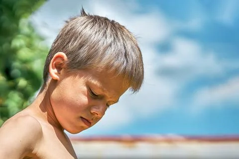 Angry boy pouts posing for camera in yard of summerhouse Stock Photos