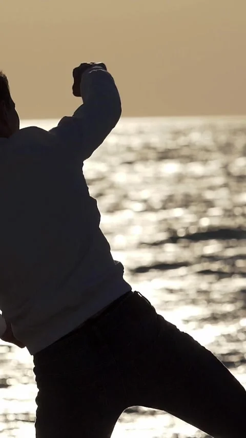 Angry boy throws a stone into the sea, seeking release from frustration Stock Footage 285540367