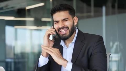 Angry businessman arguing talking on mobile phone sitting at workplace in office Stock Footage 318218827