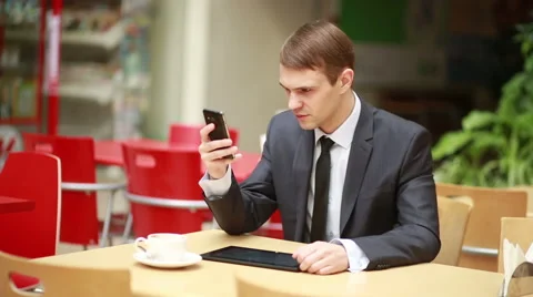 Angry businessman sitting at table in cafe and talking on mobile phone. works on Stock Footage 60967813
