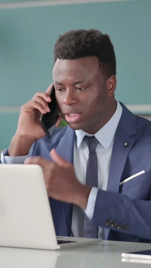 Angry Businessman Talking on Smartphone while using Laptop in Office, Vertical Stock Footage 339574724