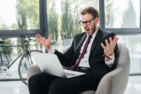 Angry businessman yelling while working on laptop at modern office Stock Photos