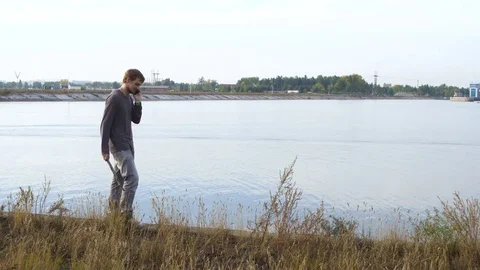 Angry caucasian guy pounding stick grass in slow motion. Lounger on the lake. Stock Footage 72590182