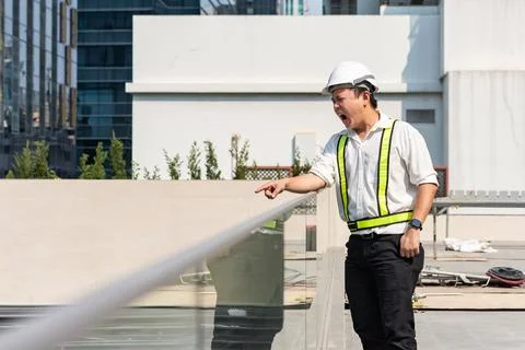 Angry construction supervisor shouting and pointing at workers while contro.. 库存照片