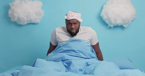 Angry dark skinned man has bad mood in morning wears blindfold casual t shirt Stock Footage 148991306