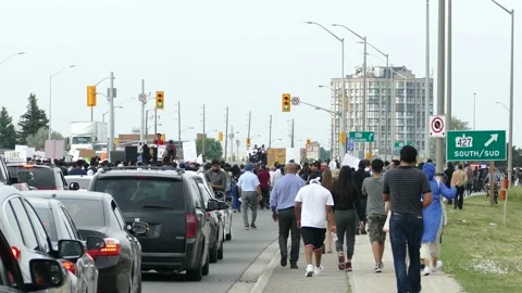 Angry demonstrators walking towards highway ramp in Mississauga, Canada Stock Footage 133975498