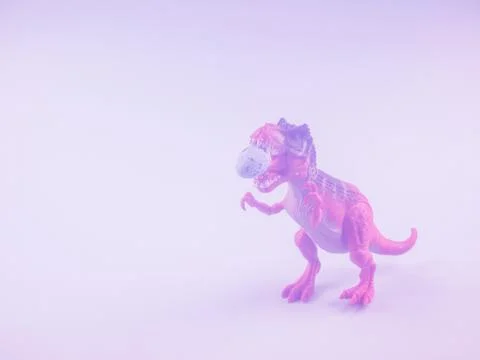 Angry dinosaur toy with easter egg in mouth. Toned Stock Photos