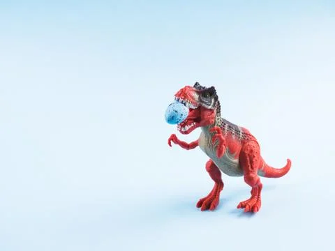 Angry dinosaur toy with easter egg in mouth Stock Photos