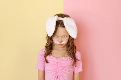 An angry, disgruntled Child in an Easter bunny costume glares maliciously Stock Photos