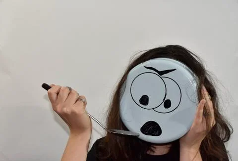 Angry emoji painted on the bottom of the kitchenware Stock Photos